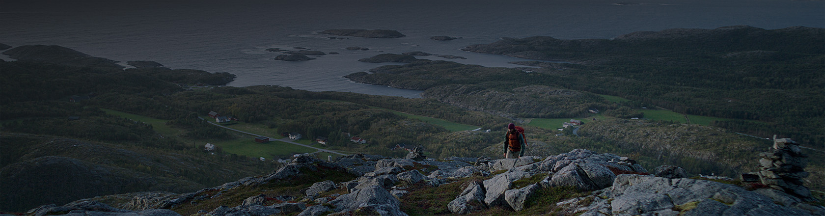 Utsikt fra Krona i Namsos, hvor vi ser en turgåer på vei opp mot toppen. Sjø og himmel i bakgrunnen.