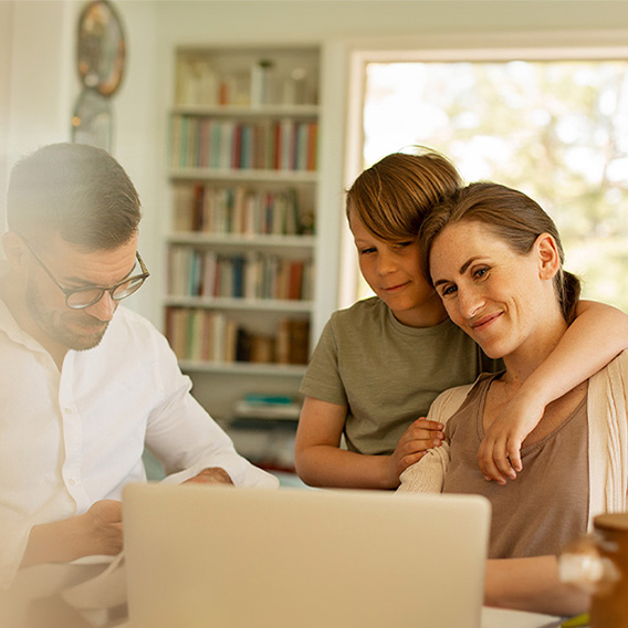 Familie sitter og koser seg ved et bord med en laptop