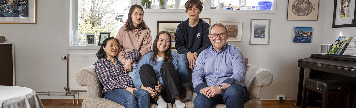 Familie på fem sitter i sofaen.